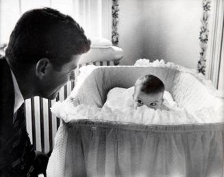 Photograph of John F. Kennedy with Caroline in Bassinet