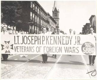 Photograph of John F. Kennedy Marching Behind Lt. Joseph P. Kennedy Jr. Veterans of Foreign Wars Post 5880 Banner